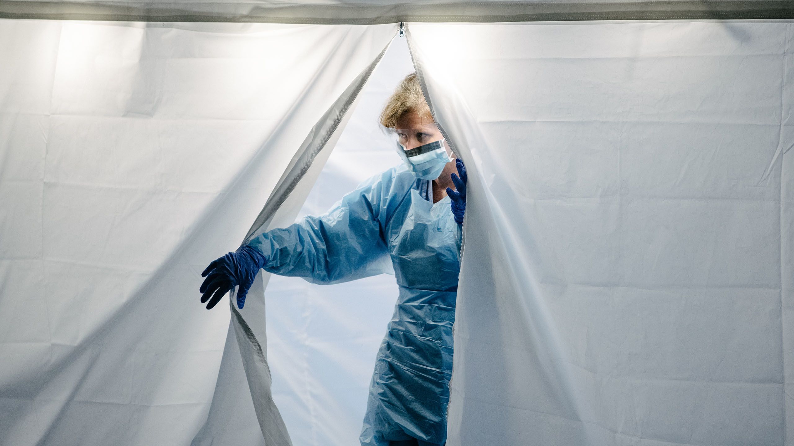 UW Medicine COVID-19 tester exits tent wearing personal protective equipment
